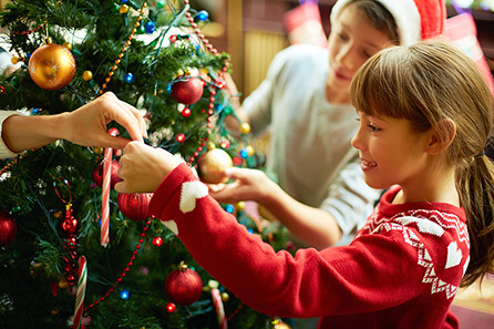 Mother giving daughter an ornament to hang on the Christmas tree