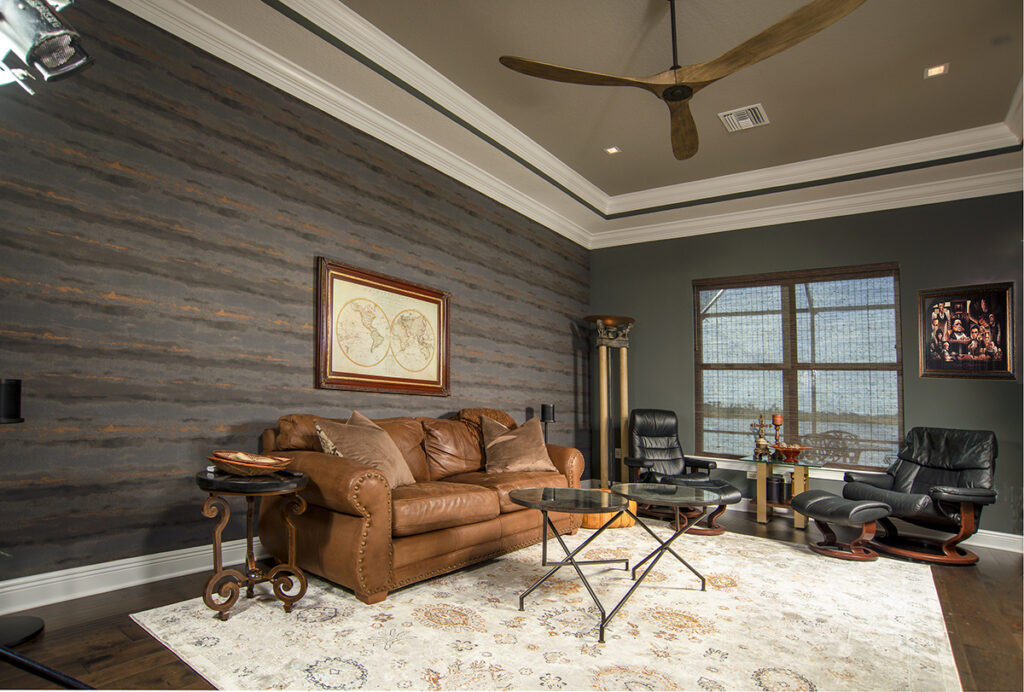 In the media room, aka Chuck Muller’s man cave, a clean, neutral palette is highlighted by subtly abstract wallpaper with a hint of copper shimmer.