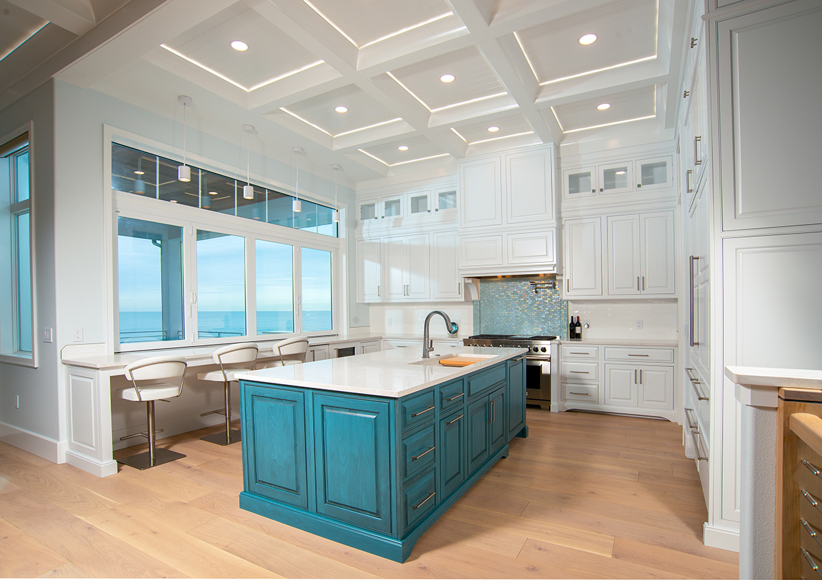 Everything, including the kitchen sink, faces the water in the magnificent space anchored by a teal kitchen island.