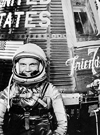 John Glenn, pilot of the Mercury Atlas 6 spaceflight, with the Mercury Friendship 7 spacecraft during preflight activities.