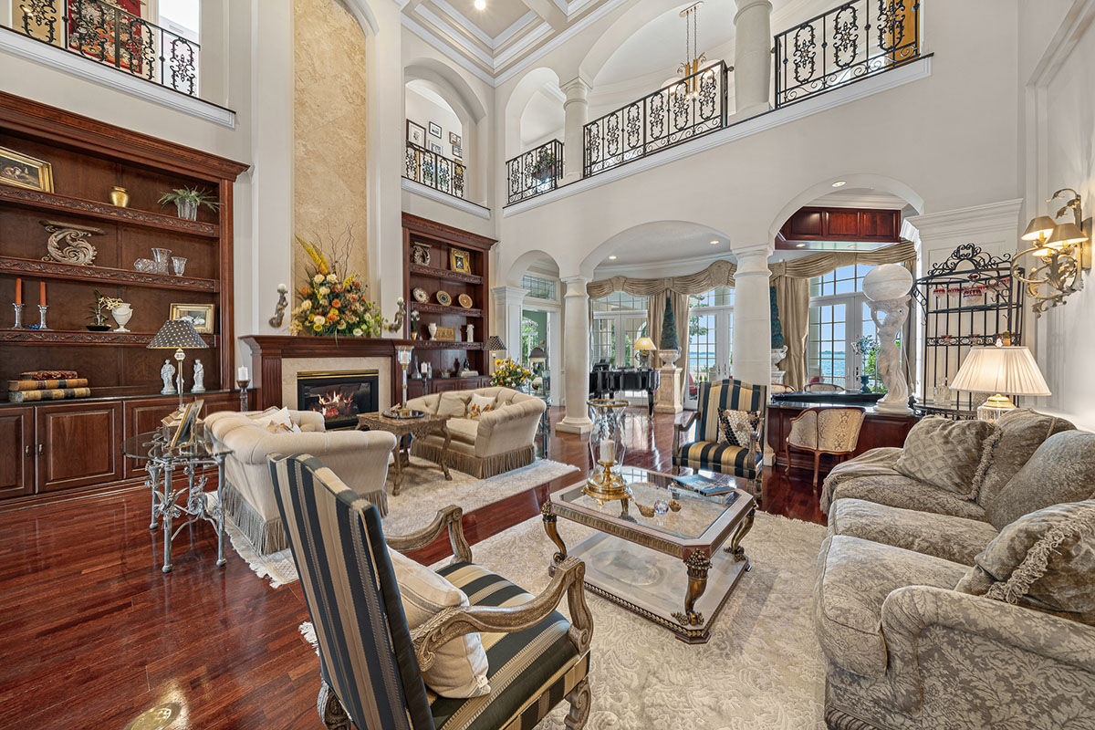 Soaring ceilings and a wraparound balcony with custom metalwork overlook the elegant living room.