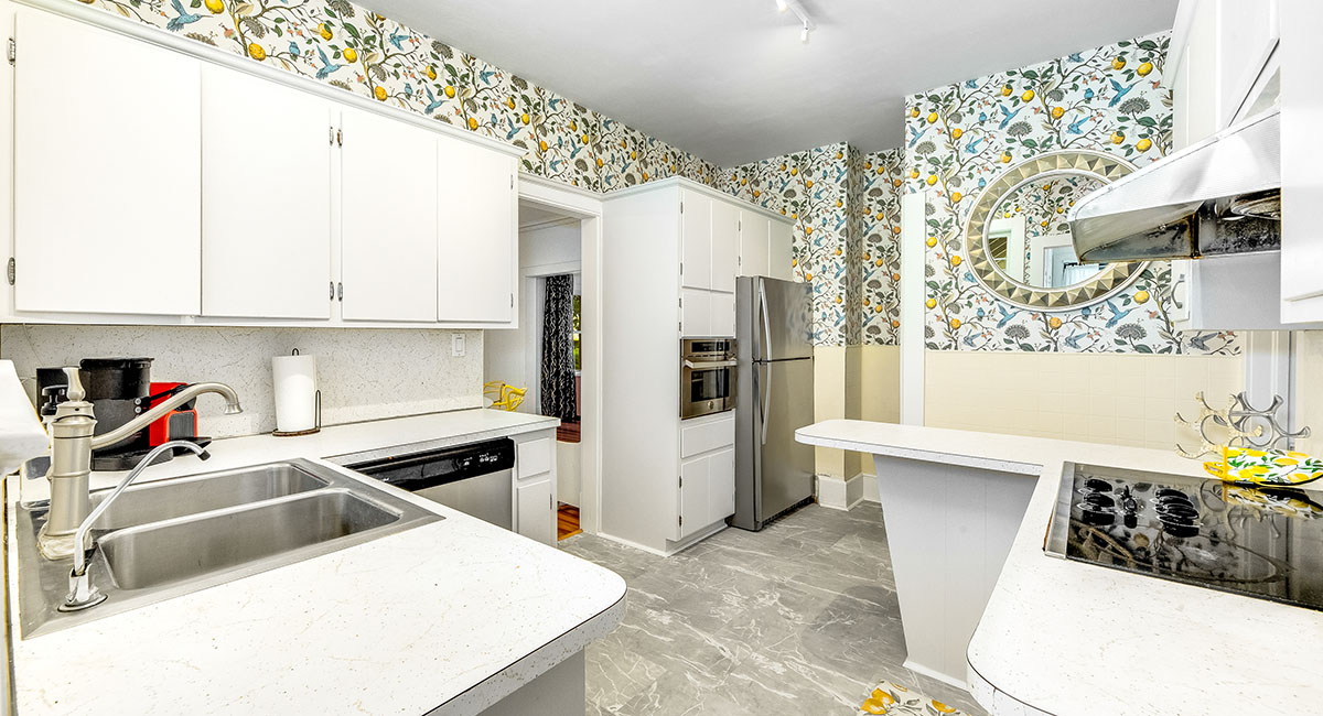 Like the rest of the house, the crisp white kitchen is ‘for the birds,’ with wallpaper carrying the avian theme. 